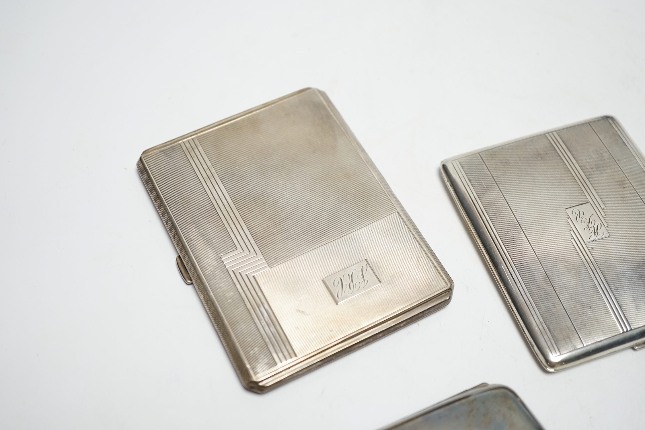 Three silver cigarette cases, including two Art Deco, largest 11.4cm.